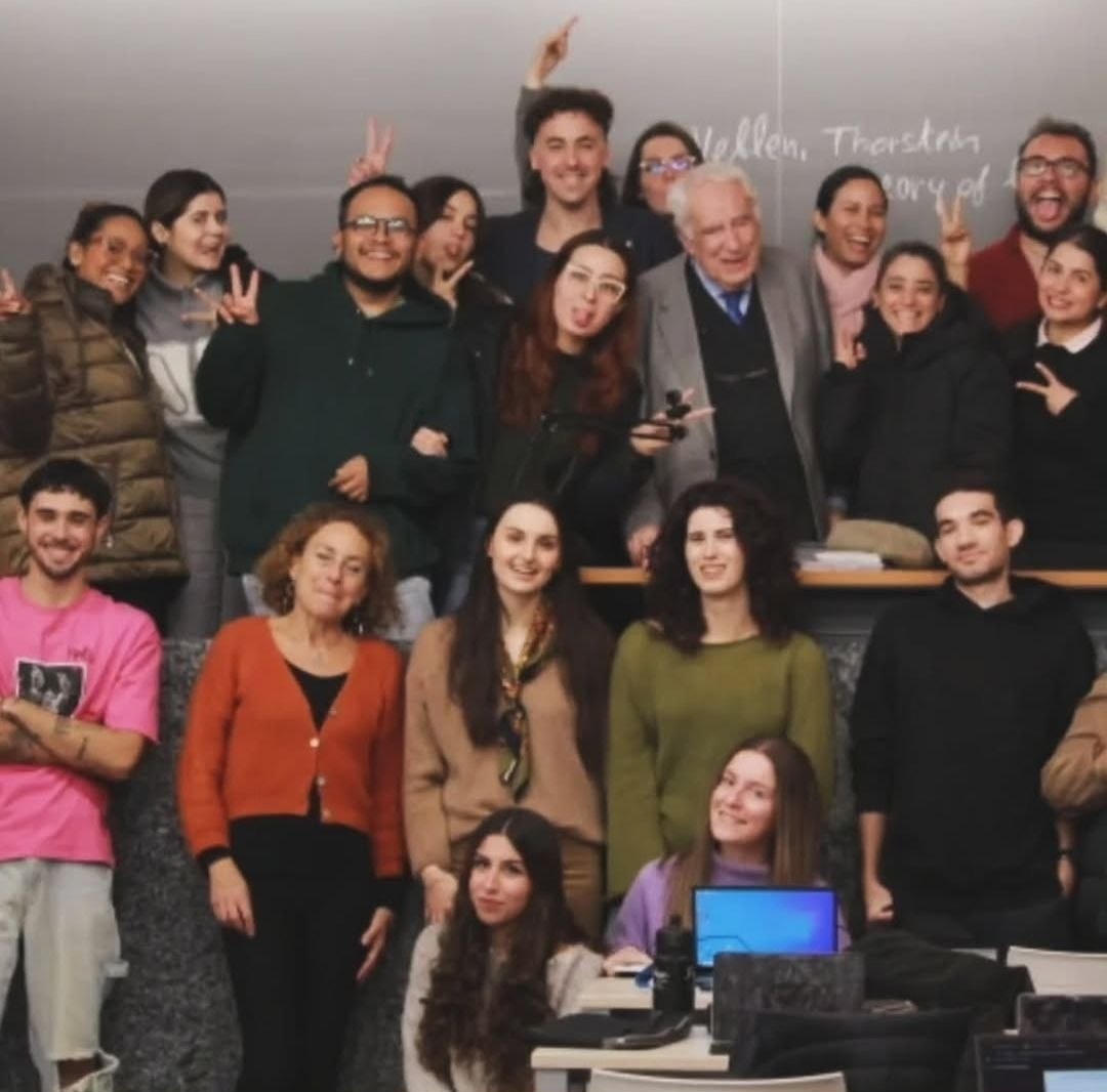 Foto de grupo en un aula universitaria con estudiantes y profesores
